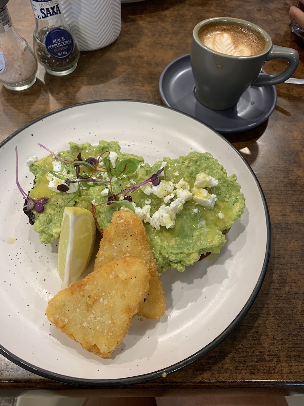 Avocado smash with a hash brown and a flat white on a timber table